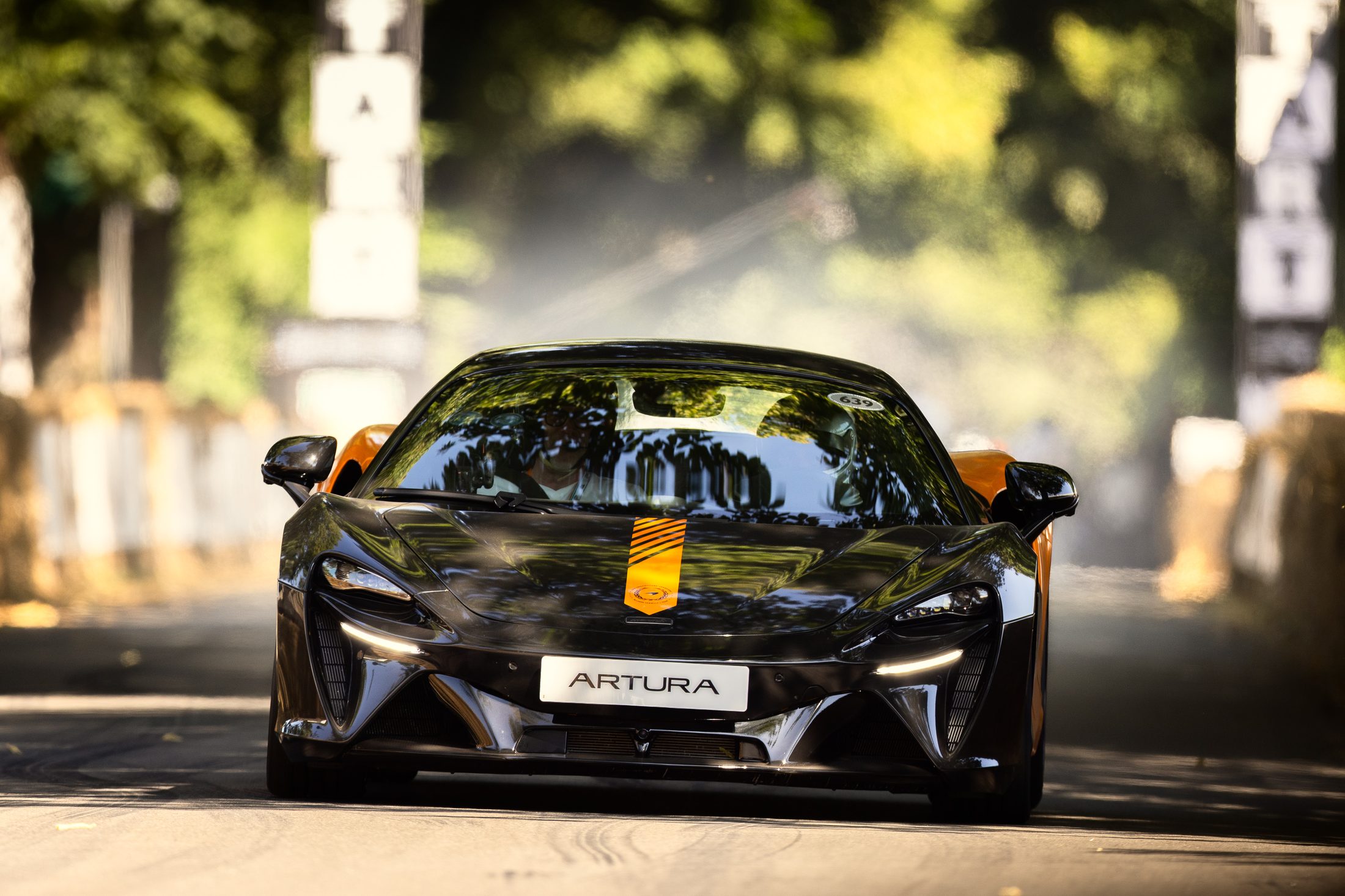 McLaren Artura climbing through dappled light at Goodwood