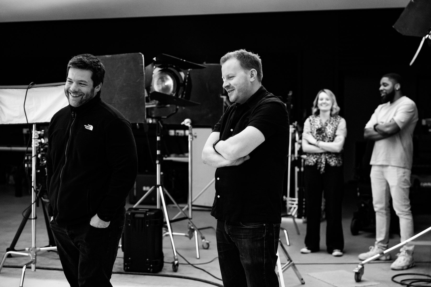 Four of the IRIS team on the studio floor between takes, lamps and stands set up around them