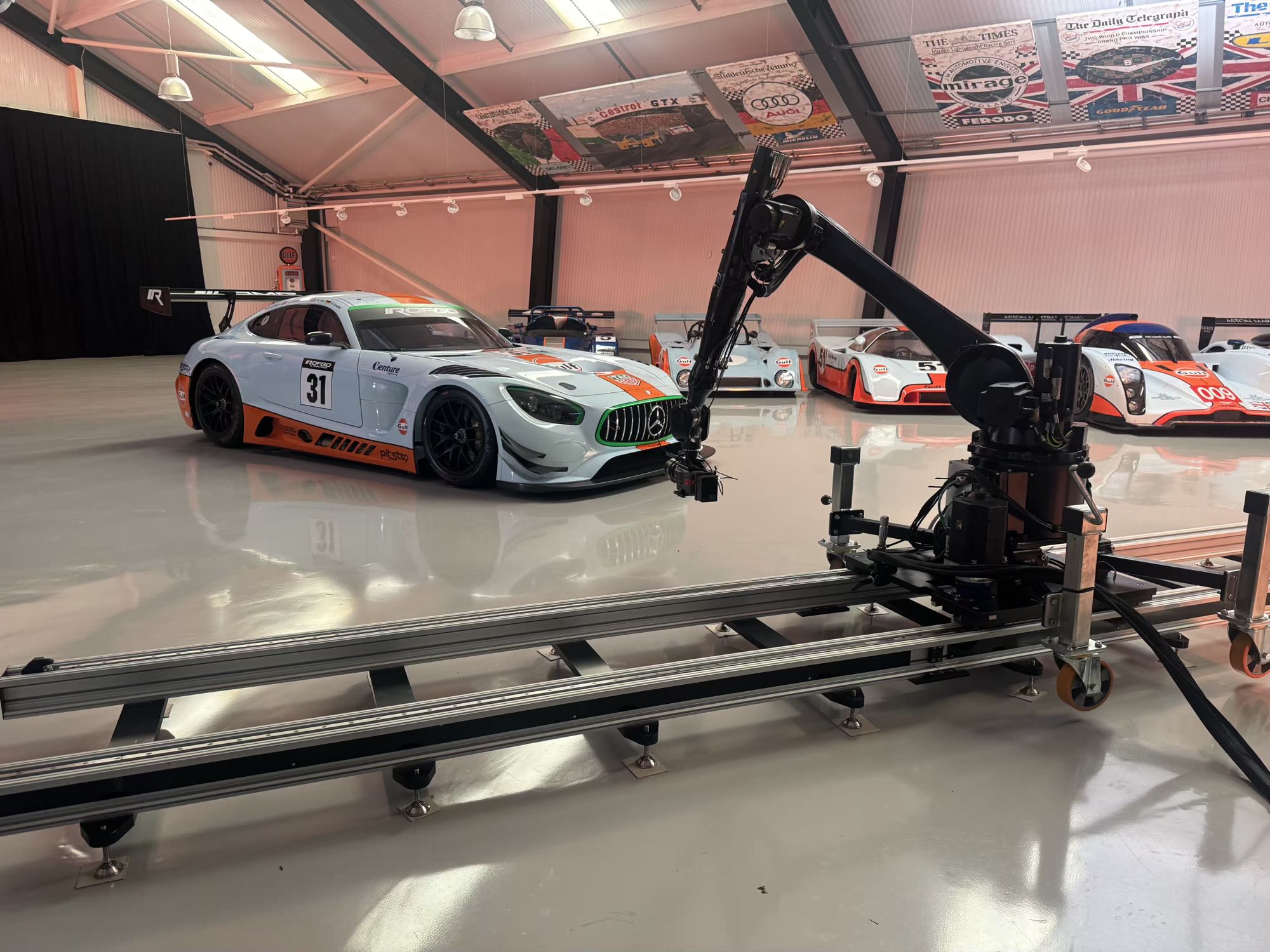 The IRIS motion-control robot on ten metres of track, aimed at a Gulf-liveried Mercedes-AMG GT3 with the private collection of Gulf race cars ranked behind it