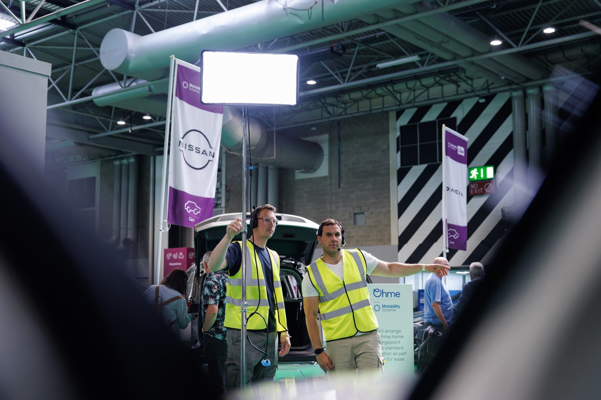 Crew rigging a lighting panel beside the Motability stands