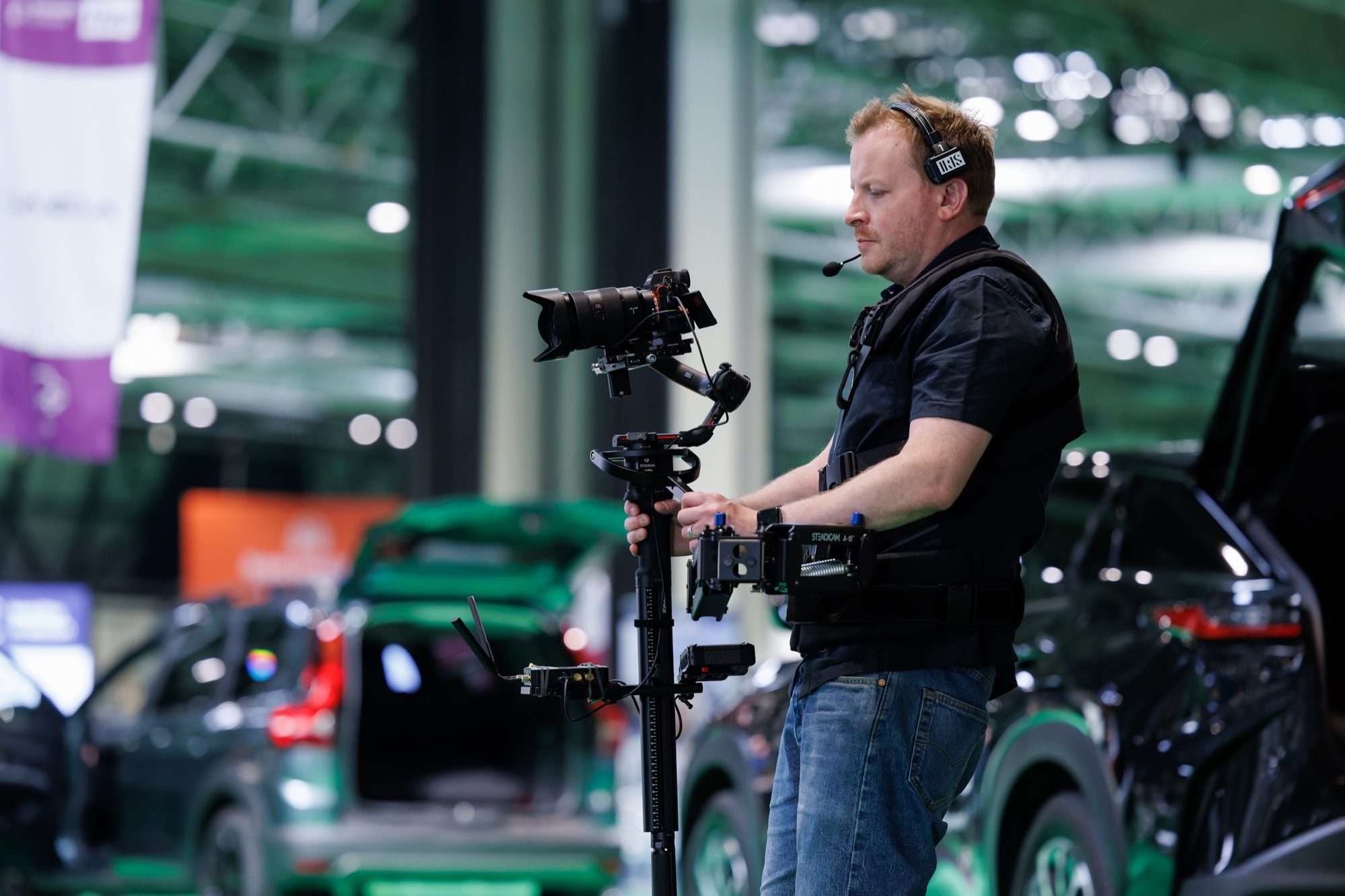 A Steadicam operator filming among the cars on the stand