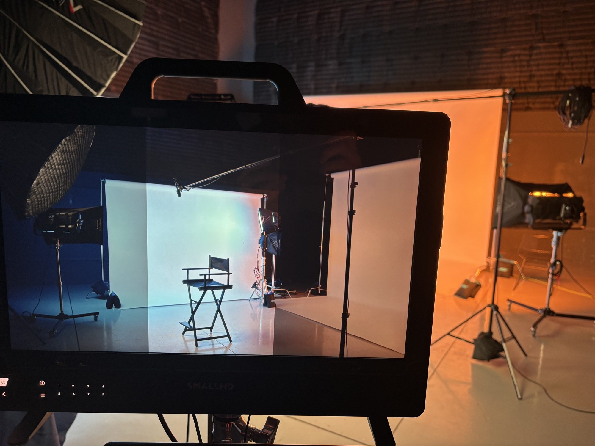 A monitor showing the lit set on the IRIS shoot, an empty director's chair on a white cyclorama, framed and ready for the driver